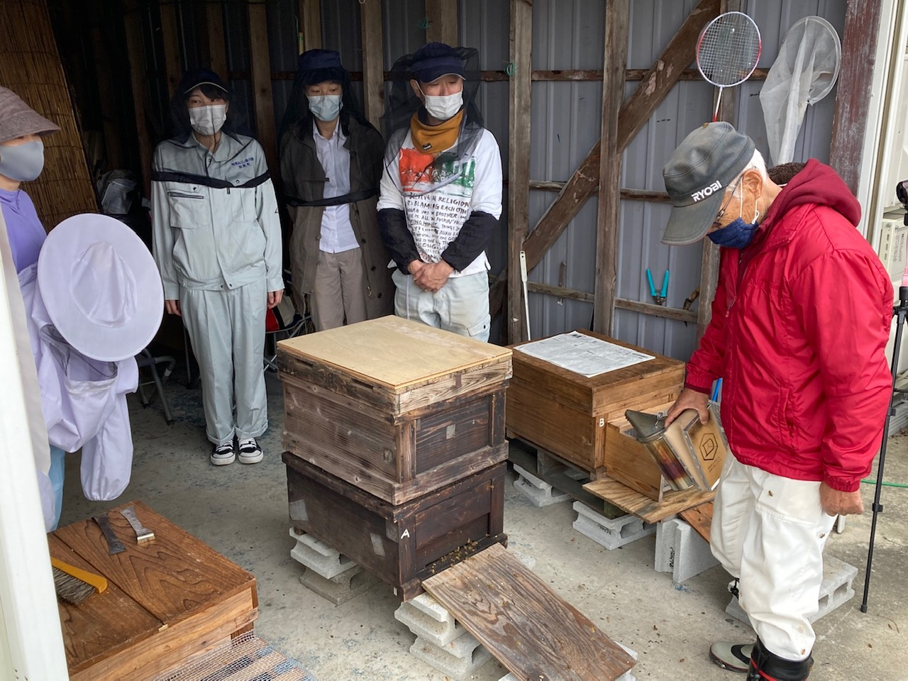 積み重なった木製の箱の傍にあつまる人達の写真