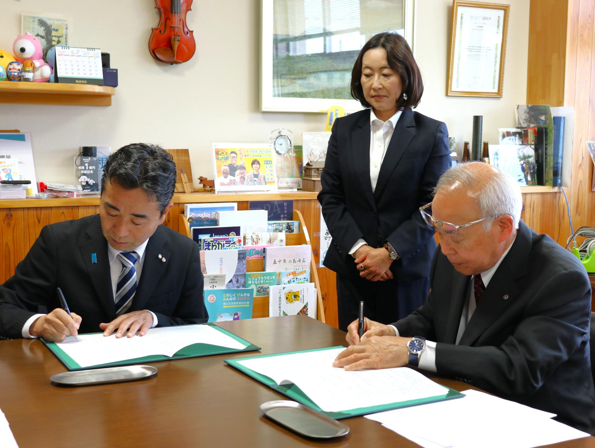 協定書にサインする両者