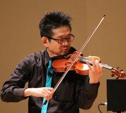 緑色のネクタイをつけてヴァイオリンを演奏する工藤さんの写真