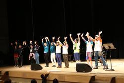 舞台の上で、出演者が一列に並んで両手を振っている写真