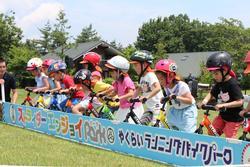 ヘルメットをかぶった子どもたちが、自転車にまたがって横一列に並んでいる写真