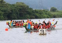 ドラゴンカヌーに乗って、鳴瀬川で水上レースを繰り広げる人たち