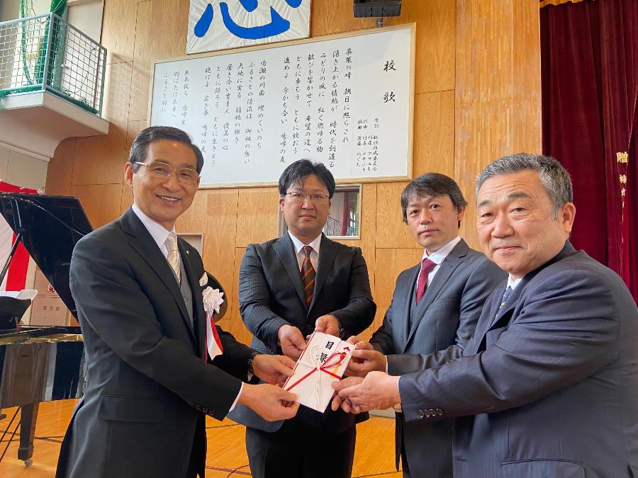 丸か建設株式会社様、小野田建設株式会社様、株式会社佐藤建設様から寄贈した校歌額の前で猪股町長へ目録が手渡されました