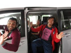 笑顔の男性選手たちが、乗用車の中からカメラに向かって手を振っている写真