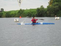 選手が青いカヌーに乗り、パドルを使って漕いでいる写真
