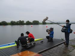 川の岸辺でカヌーに乗り込む男性二人とその様子をテレビ取材する男性二人の写真