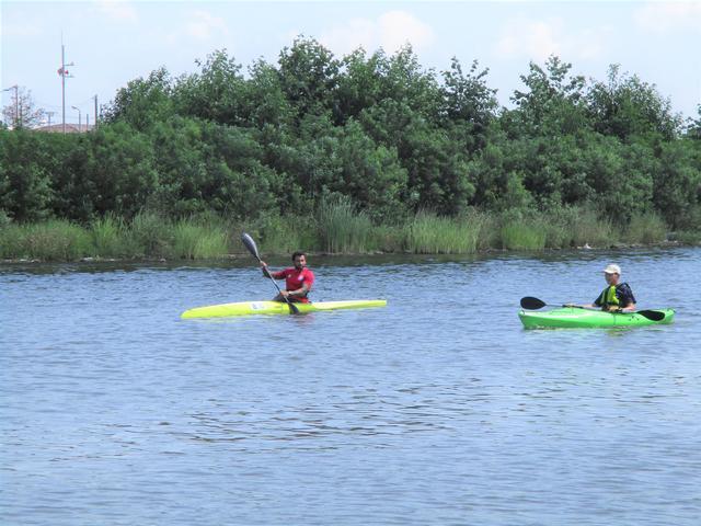 川に浮かぶカヌーを漕いでいる2人の男性の写真