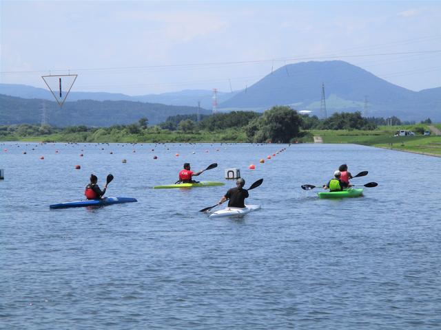 山を背景に5人がカヌーを漕いでいる写真