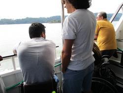 遊覧船から海を眺める男性三人を後ろから撮った写真