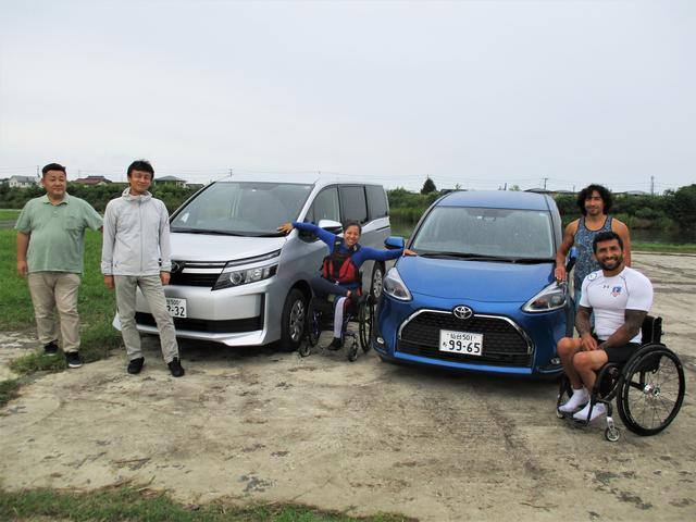 二台の車を囲んで、選手たちとボランティアたちがこちらに笑顔を向けている写真