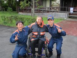 屋外で並んで映る車椅子の女性と消防隊員の記念写真