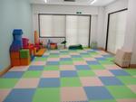カラフルな床の部屋に様々な形や色のおもちゃのブロックが置かれている写真