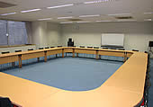 木の机が口の字型に並んでいる、広い会議室の写真