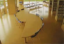 特徴的な形をしたテーブルの脇にたくさん椅子が置かれている写真