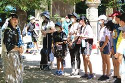 帽子をかぶった生徒たちが、横に並んで説明を受けている写真