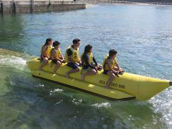 子どもたちが黄色いバナナボートにまたがり、水の上を進んでいる写真