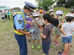 警察官が横に立ち、子どもたちがヘルメットをかぶっている写真